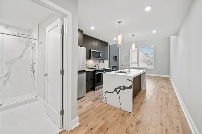 Contemporary kitchen with sleek black cabinets, modern appliances, and an island with a unique marble design in a stylish apartment.
