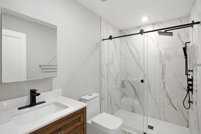 Luxurious bathroom featuring a sleek walk-in glass shower with elegant marble walls and modern fixtures.