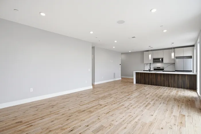 Spacious open-concept apartment with elegant wood flooring, modern kitchen with sleek cabinetry, and bright natural lighting.