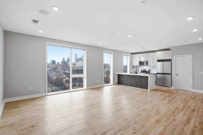 Modern open-concept apartment with sleek kitchen and panoramic city views, featuring elegant hardwood floors and abundant natural light.