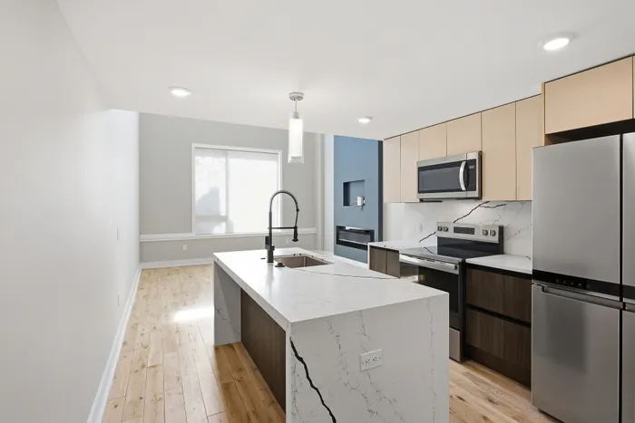 Elegant modern kitchen with sleek marble countertops, stainless steel appliances, and abundant natural light.