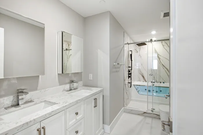 Luxurious modern bathroom featuring elegant double sinks, sleek fixtures, and a spacious glass-enclosed shower with marble accents.