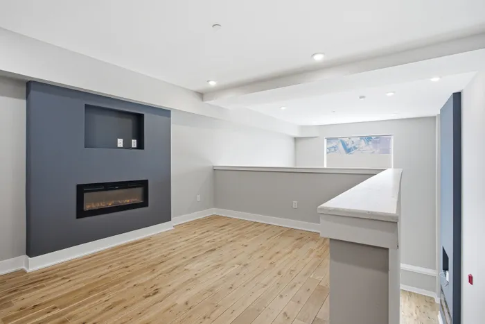 Modern loft-style living room featuring sleek hardwood floors, a contemporary built-in fireplace, and ample natural light.