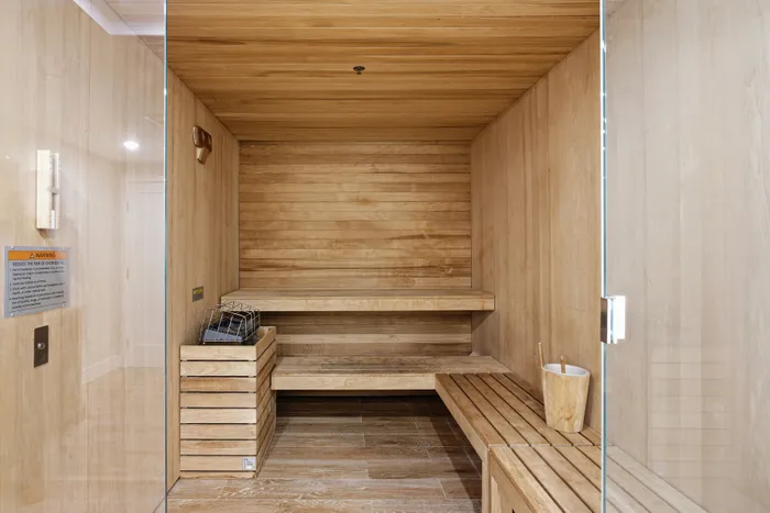 Luxurious modern sauna with wooden benches and sleek glass door, perfect for relaxation.