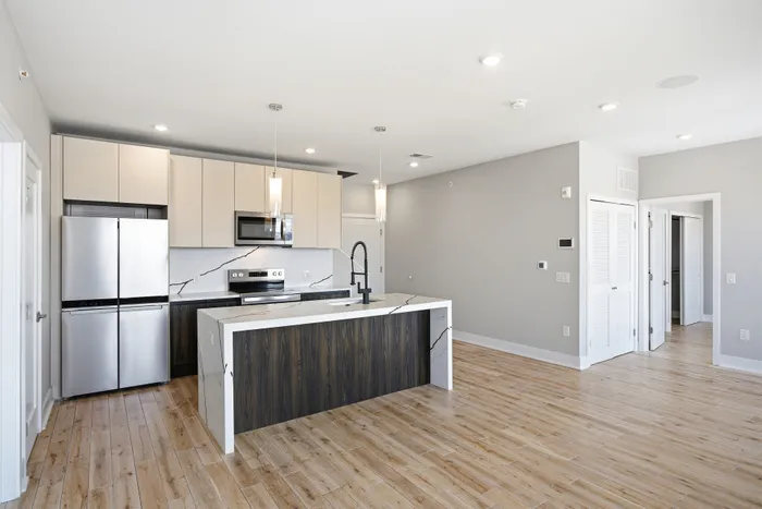 Sleek modern kitchen with stainless steel appliances, stylish pendant lights, and elegant wood flooring.