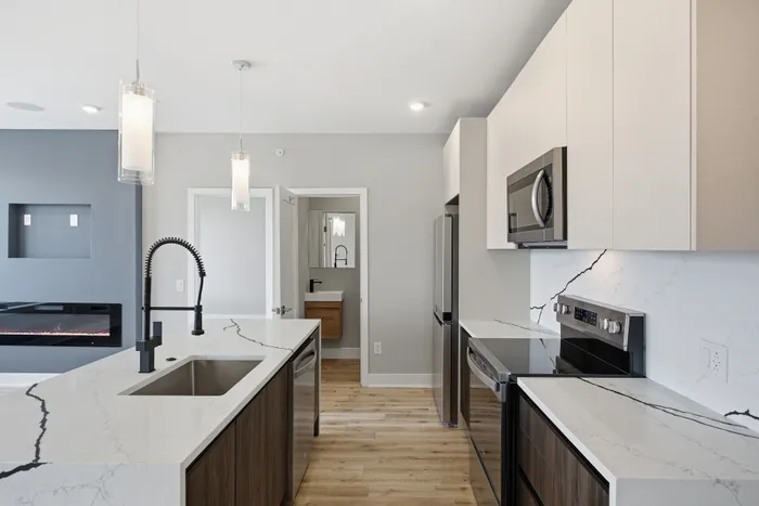 Modern kitchen with sleek white marble countertops, high-end stainless steel appliances, and stylish pendant lighting.