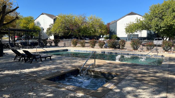 Inviting outdoor pool area with sun loungers, a relaxing hot tub, and lush greenery providing a serene ambiance.