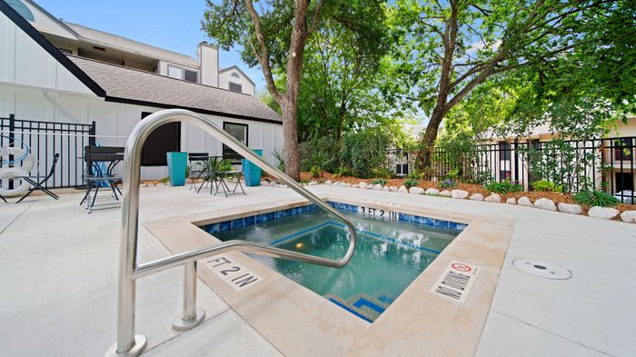 Charming outdoor hot tub area with lush green surroundings and stylish patio seating, perfect for relaxation.