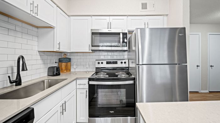Modern kitchen with sleek stainless steel appliances, elegant white cabinets, and a stylish subway tile backsplash.