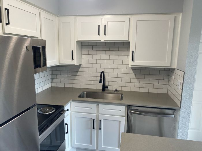 Contemporary kitchen with sleek white cabinetry, modern stainless steel appliances, and elegant subway tile backsplash.