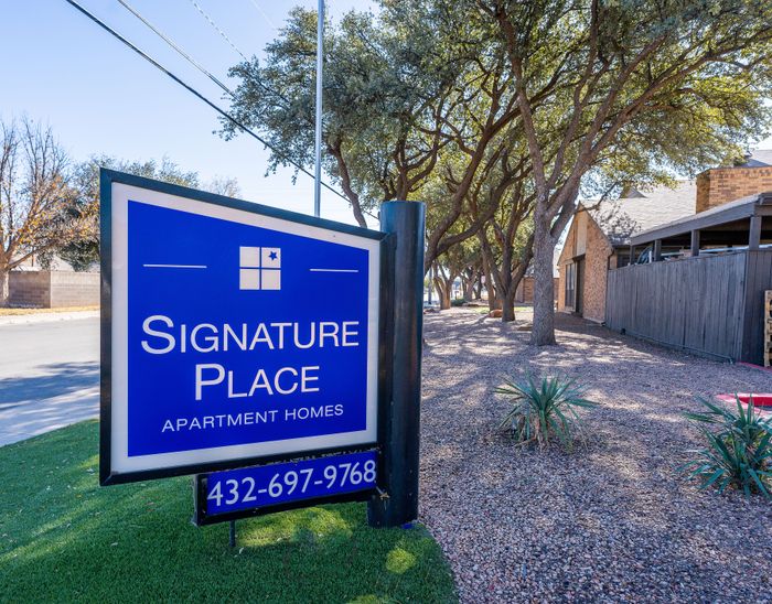 Inviting entrance to Signature Place Apartment Homes, surrounded by lush trees and a tranquil setting.