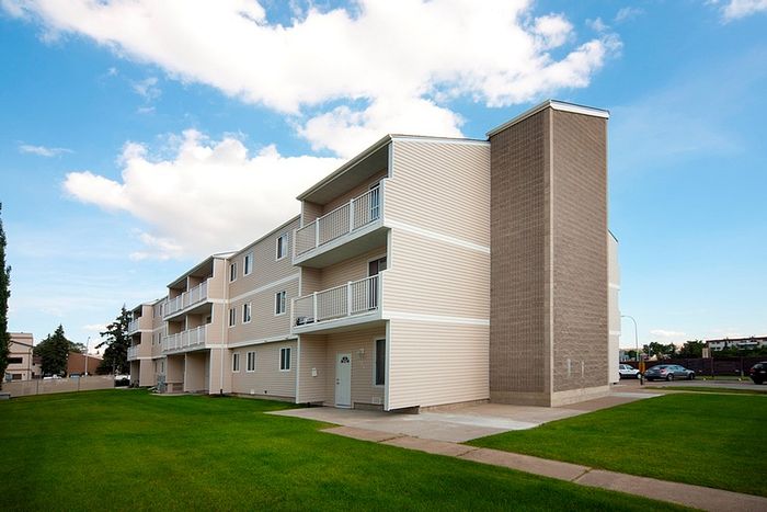 Charming apartment building with spacious balconies and manicured lawns under a clear blue sky.