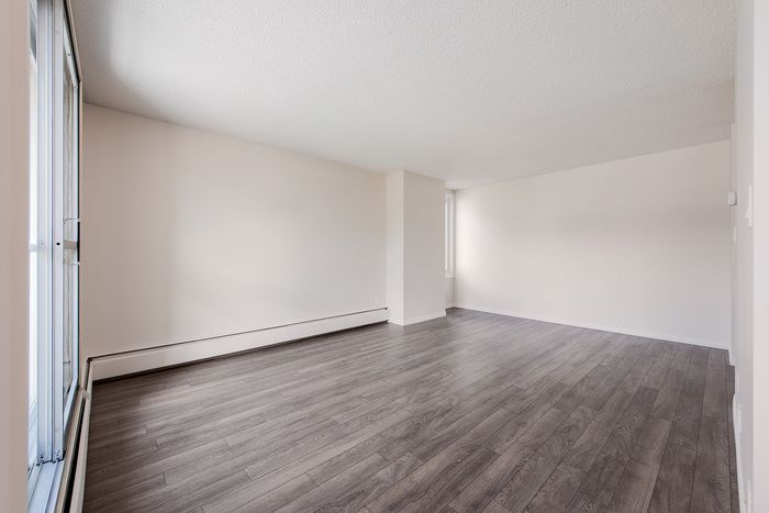Spacious and bright living area with modern laminate flooring and abundant natural light from large windows, ideal for stylish urban living.