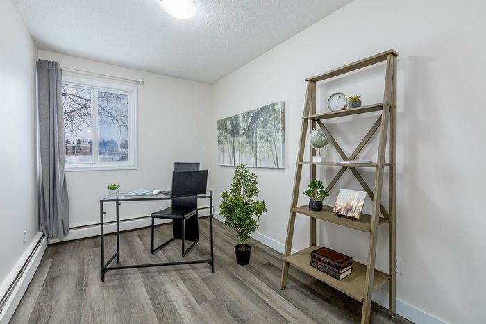 Bright and inviting home office with modern decor, featuring a sleek desk, stylish bookshelf, and a large window offering natural light.