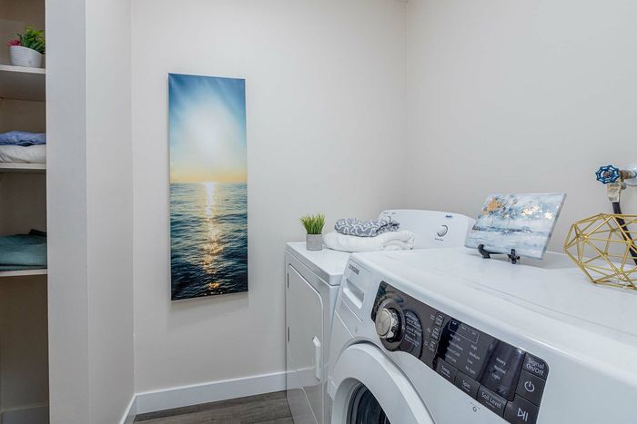 Chic laundry room with modern appliances, ocean-themed wall art, and stylish decor, perfect for a contemporary home.