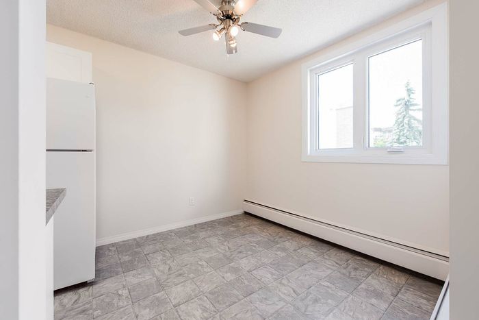 Bright, modern kitchen with ample natural light, featuring a large window, ceiling fan, and sleek tile flooring.