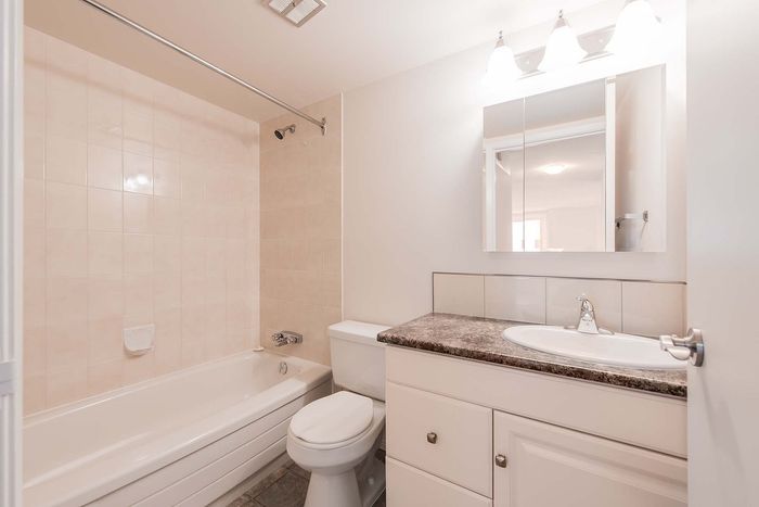 Modern bathroom with elegant lighting, sleek vanity, and inviting bathtub in a pristine apartment setting.