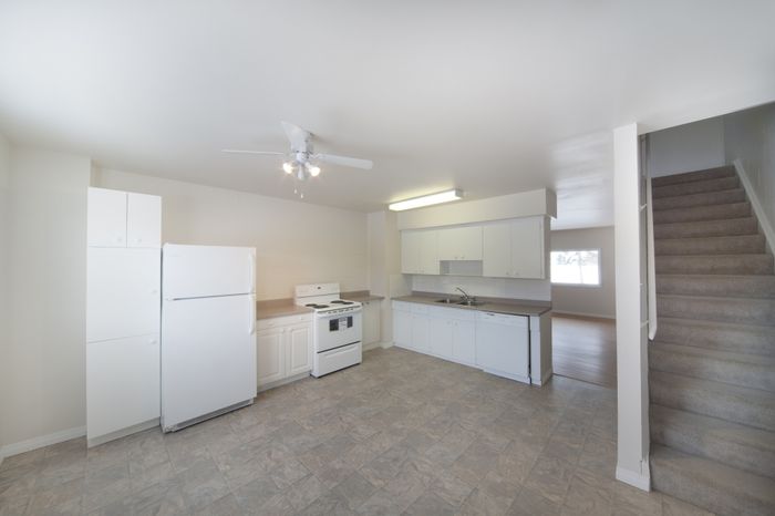 Bright and spacious kitchen with modern appliances, tiled flooring, and adjacent staircase in a stylish duplex apartment.