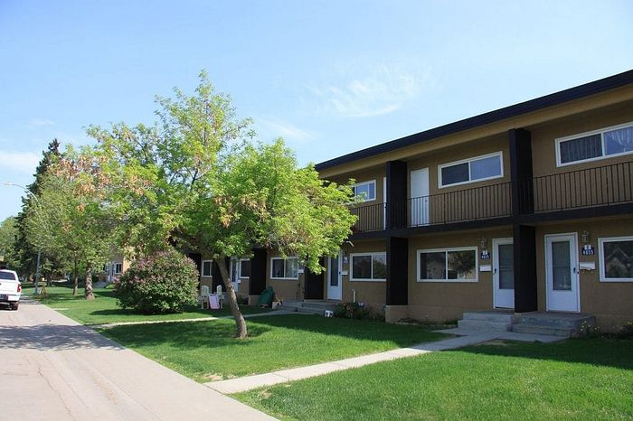 Charming townhouse complex with modern two-story units, surrounded by lush greenery and a vibrant, peaceful neighborhood setting.