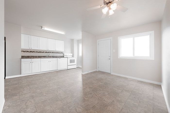 Bright and airy open-concept kitchen and living space with modern white cabinetry and large windows.