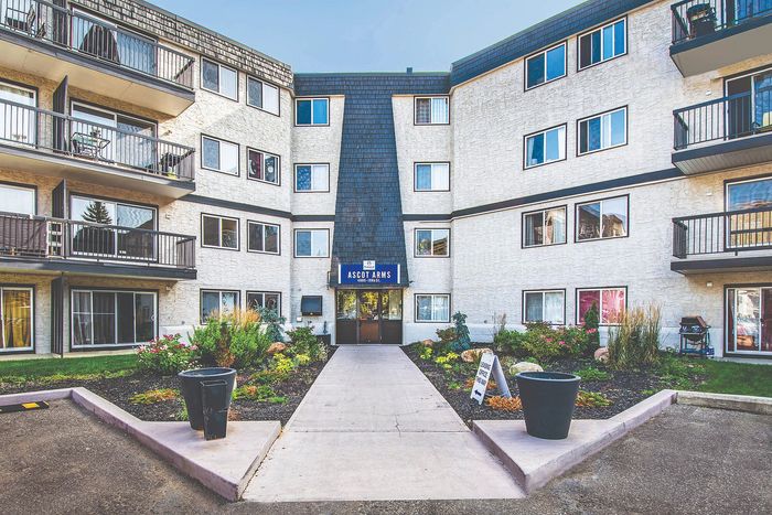 Inviting apartment building exterior with charming balconies, lush landscaping, and welcoming entrance at Ascot Arms.