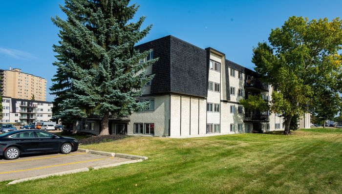 Charming apartment complex with spacious green lawns and mature trees, perfect for serene living.