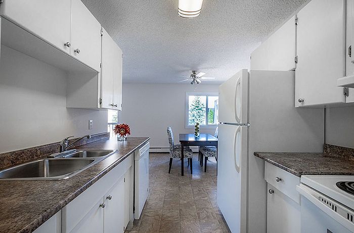 Bright and inviting kitchen with modern white cabinetry, sleek countertops, and a cozy dining area with natural light streaming in.