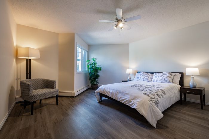 Inviting bedroom with modern decor, featuring a cozy bed, elegant lighting, and a stylish chair, perfect for relaxation.