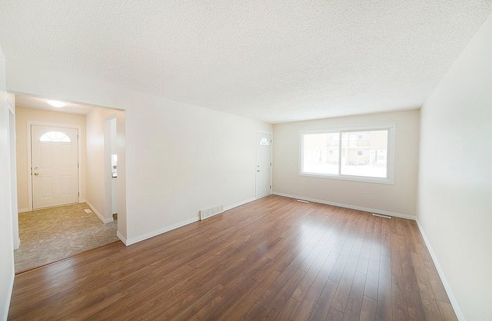 Inviting open-concept living space with abundant natural light, featuring sleek hardwood flooring and a welcoming entryway.