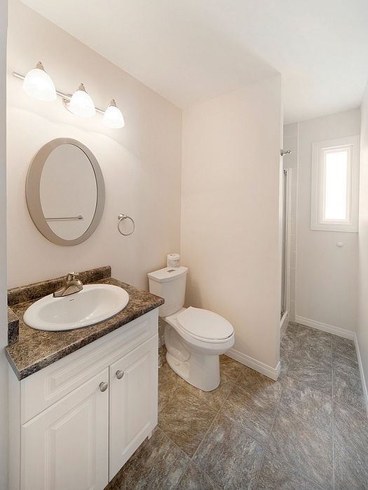 Bright and modern bathroom featuring a sleek vanity, elegant lighting, and a spacious shower.