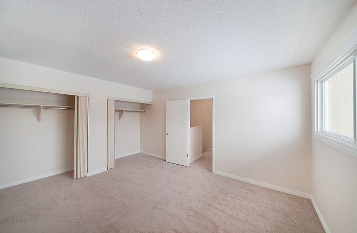 Bright bedroom with plush carpeting, ample closet space, and natural light streaming through large window.