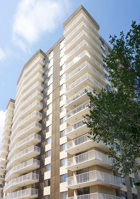 Modern high-rise apartment building with multiple balconies, offering panoramic views and located in a vibrant urban area.