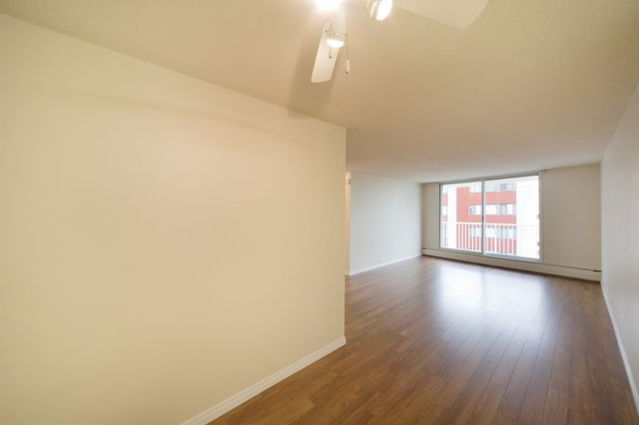Bright and spacious living area with elegant hardwood floors and large window offering city views.