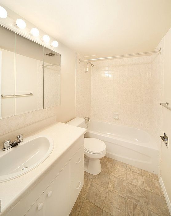 Bright, modern bathroom with sleek vanity, full-size mirror, and elegant bathtub, ideal for relaxation.