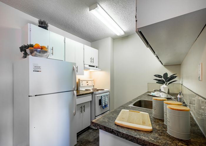 Chic kitchen featuring modern white cabinets, sleek countertops, and an inviting atmosphere created by bright lighting and stylish decor elements.