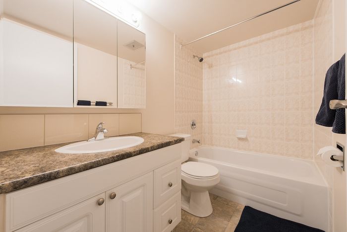Elegant bathroom with modern vanity, sleek white cabinetry, and a luxurious bathtub, enhanced by warm lighting and tasteful tilework.