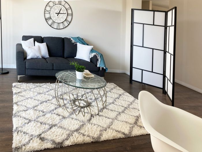 Chic living room with elegant gray sofa, stylish glass coffee table, and modern decor in bright, inviting apartment.