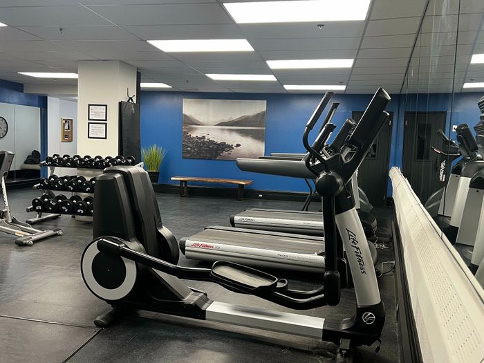 Modern gym with state-of-the-art equipment, including treadmills and free weights, in a sleek, blue-accented fitness center.