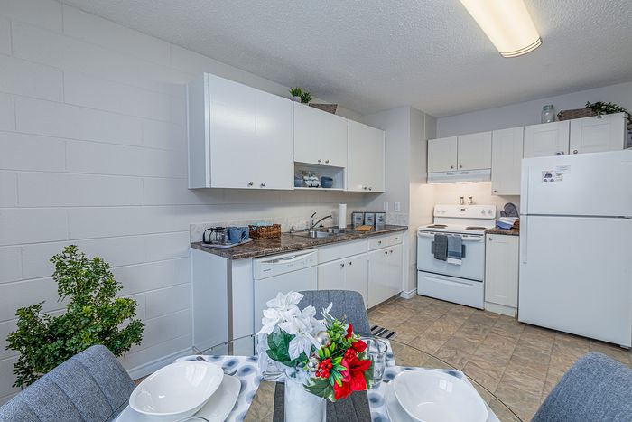 Charming kitchen with white cabinetry and modern appliances, complemented by a cozy dining area featuring stylish decor and natural lighting.