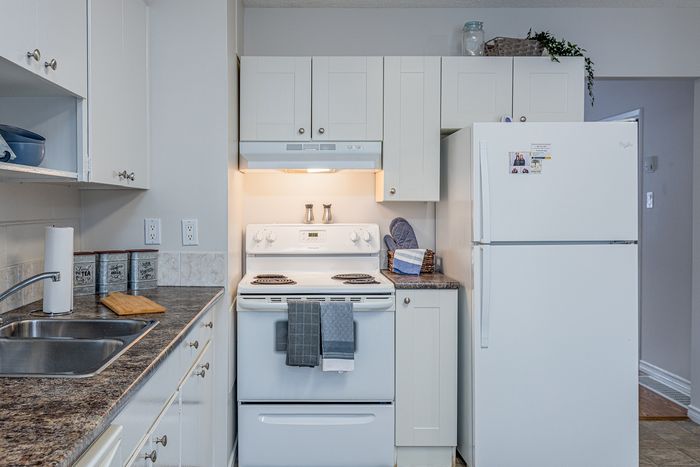 Charming and practical kitchen with crisp white cabinets, modern appliances, and a sleek countertop.
