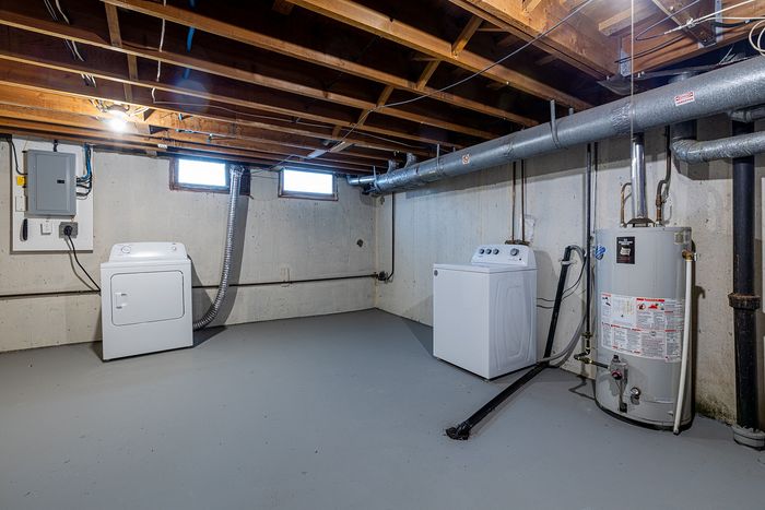 Spacious basement laundry area with modern washer, dryer, and utility setup perfect for storage and functionality.