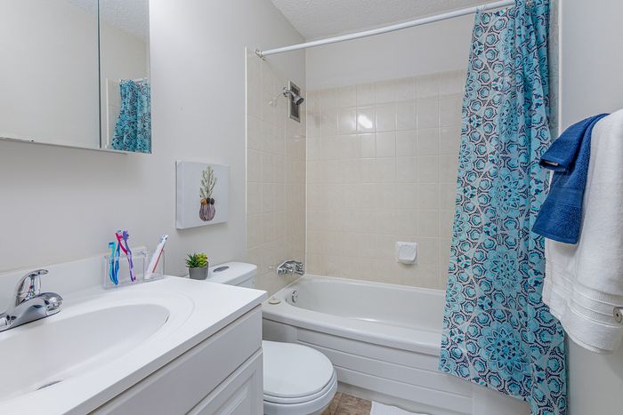 Bright and modern bathroom with elegant blue accents, featuring a pristine bathtub and stylish decor.