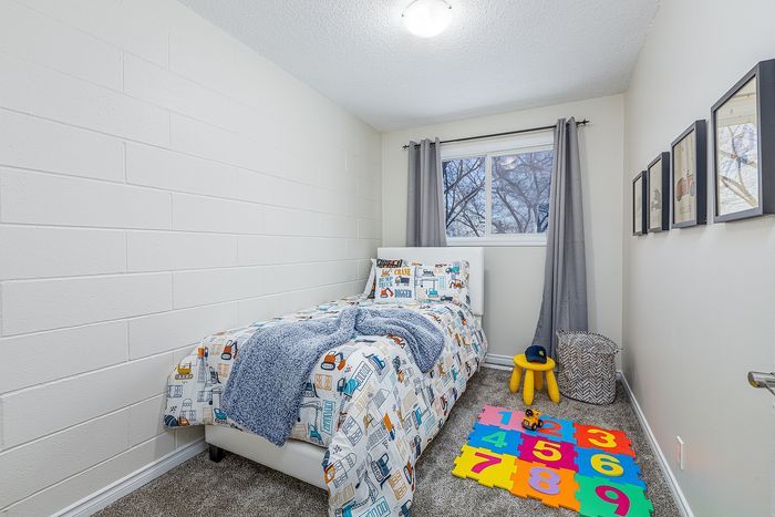 Inviting children's bedroom with cozy twin bed, playful decor, and vibrant educational mats for a cheerful atmosphere.