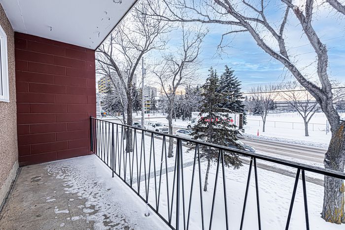 Charming balcony view showcasing a snowy urban landscape with pristine trees and a tranquil street scene.