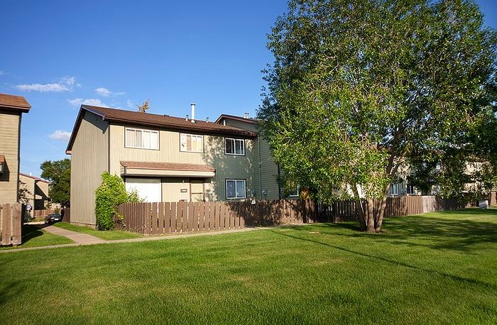 Charming townhouse with lush green lawn and abundant natural light, creating an inviting residential atmosphere.