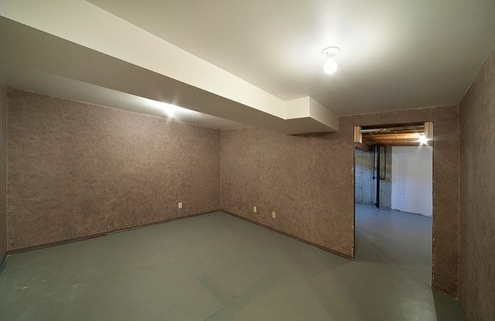 Spacious, modern basement with elegant textured walls and ample lighting, ideal for customization into a cozy living space.
