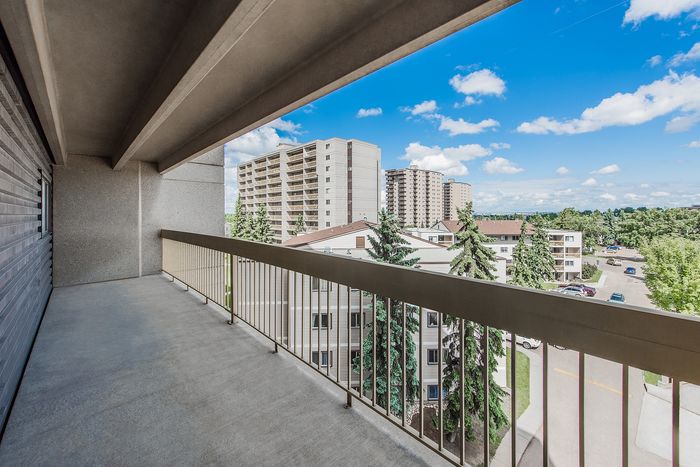 Spacious balcony with scenic views of urban skyline and lush greenery, perfect for relaxation.
