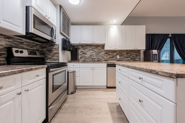 Modern kitchen with sleek stainless steel appliances, elegant white cabinetry, and a stylish mosaic backsplash.