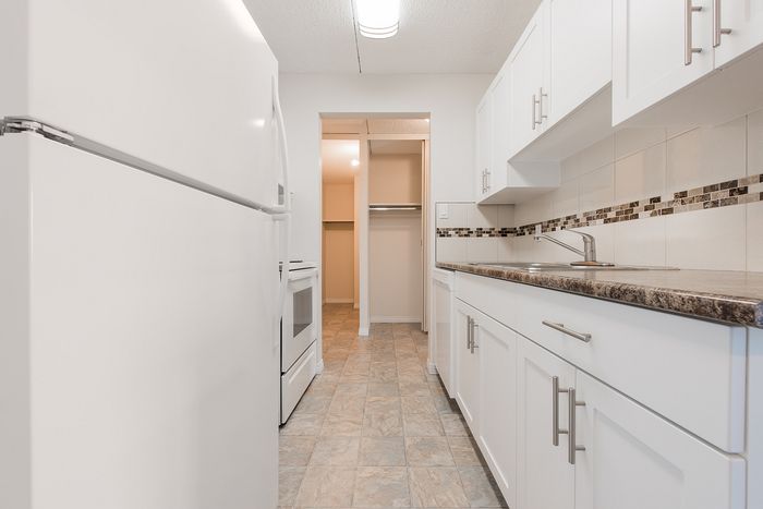 Bright and modern kitchen with sleek white cabinetry, elegant tile backsplash, and spacious countertops.