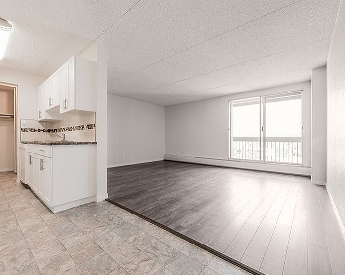 Bright and airy open-concept living space with sleek flooring and modern kitchen, featuring large windows perfect for natural light.